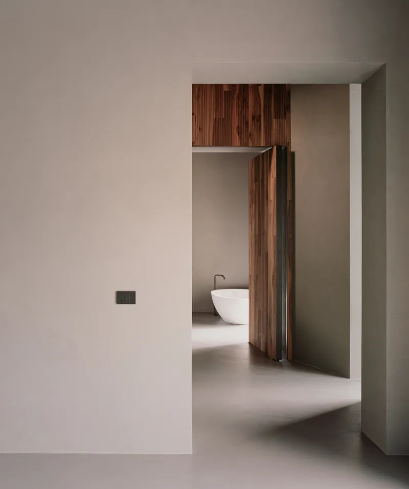 View through doorway into a bathroom with freestanding white tub and timber cabinetry