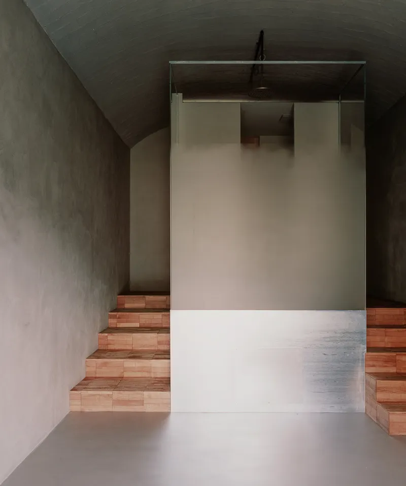 Timber-faced staircase framed by plastered walls and vaulted ceiling with soft overhead light