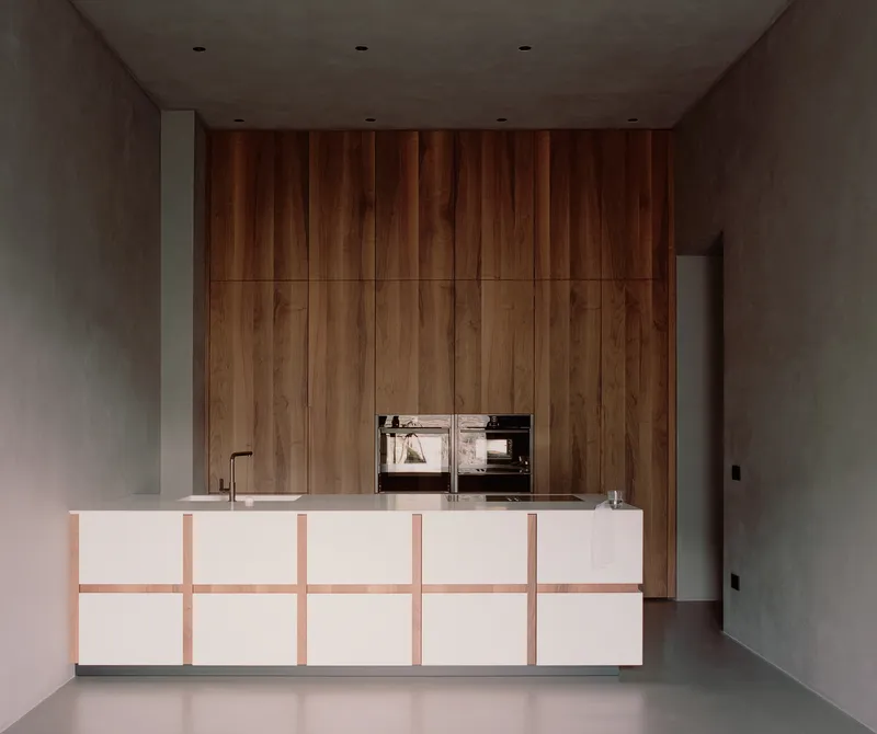 Kitchen island with white panels and timber detailing against a full-height wood cabinet wall