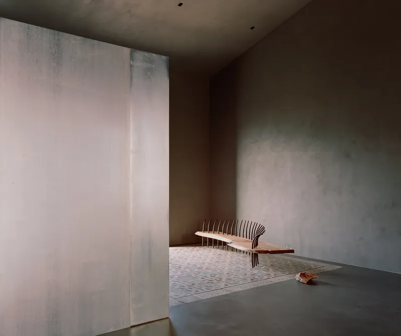Interior room with slatted timber bench against rendered plaster walls with textured trowel marks
