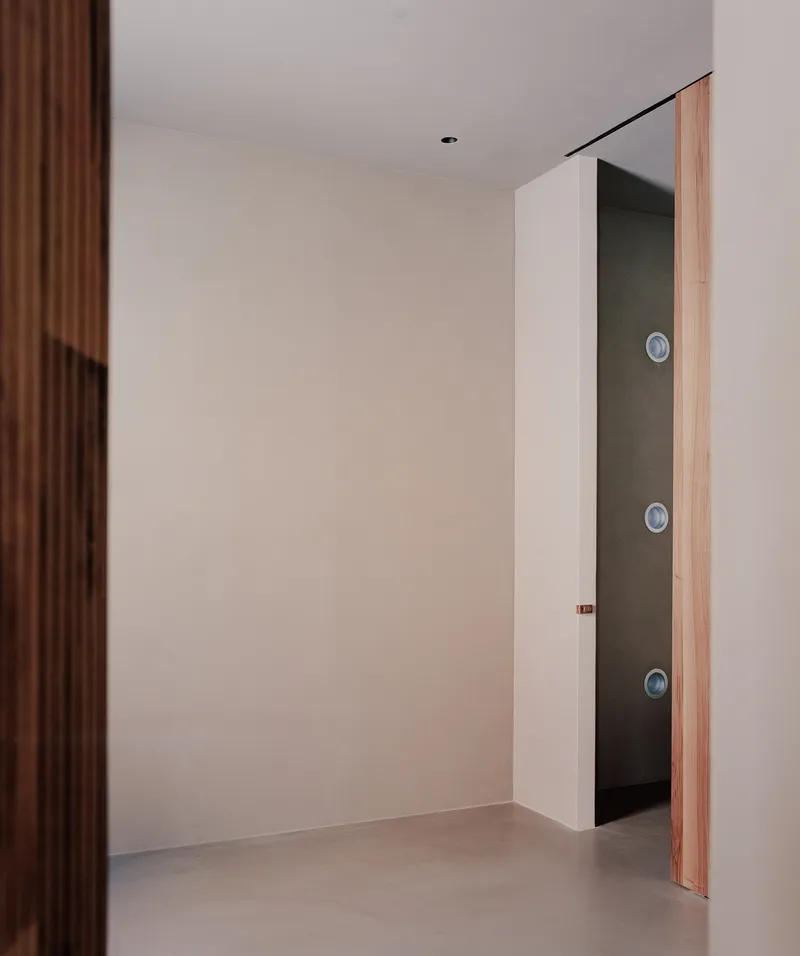 Timber-edged doorway opening into a dark corridor with three circular wall fixtures
