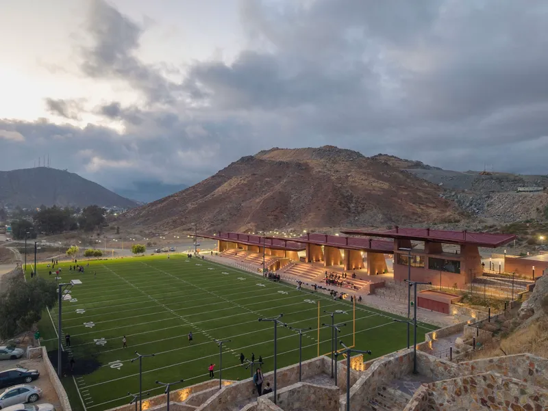 Aerial view of the sports complex with illuminated covered seating along the field at twilight