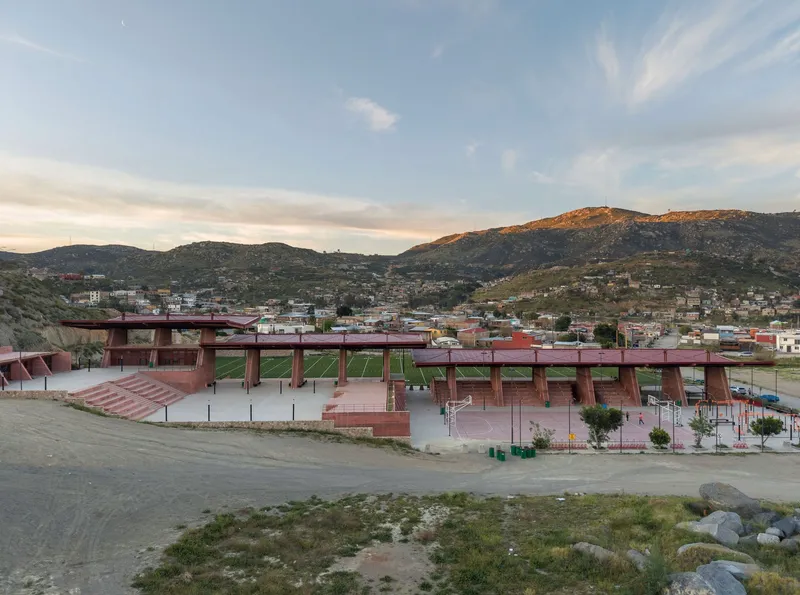 Distant view of the linear canopy structures spanning the athletic complex against hillside development