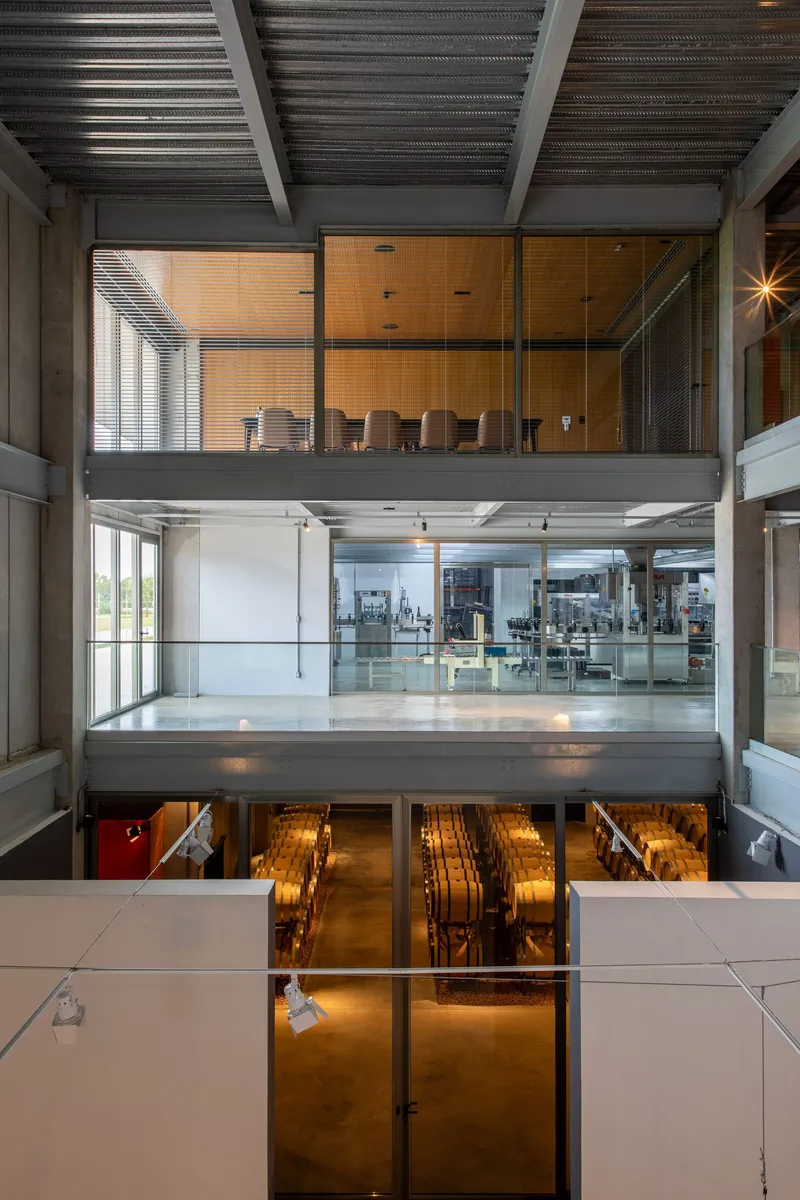 Three-story interior atrium showing stacked floors with concrete beams and glass-walled production space below