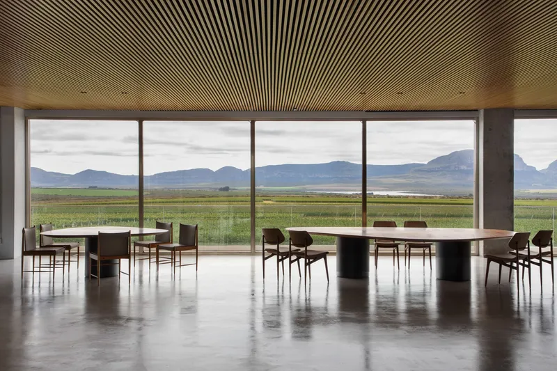 Dining room with slatted timber ceiling and floor-to-ceiling windows overlooking vineyards and distant mountains