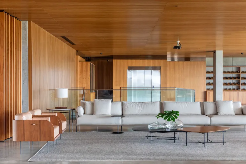 Lounge area with vertical timber slat wall and glass guardrail under a wood-paneled ceiling
