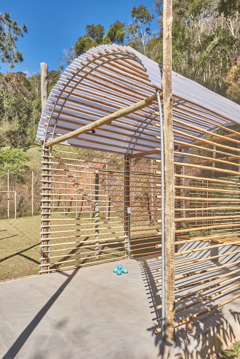 Exterior view of the arched timber and translucent panel canopy rising above horizontal wooden slat walls