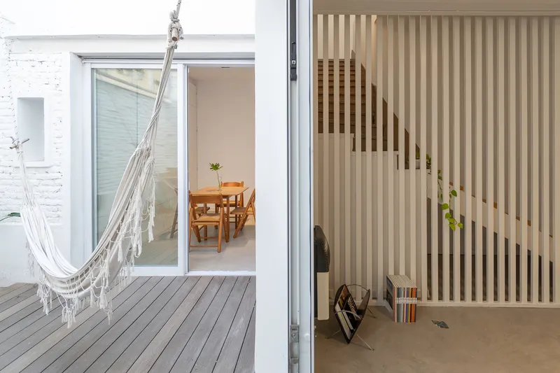 Timber courtyard deck with a hammock hung beside a vertical wood slat screen framing the interior view