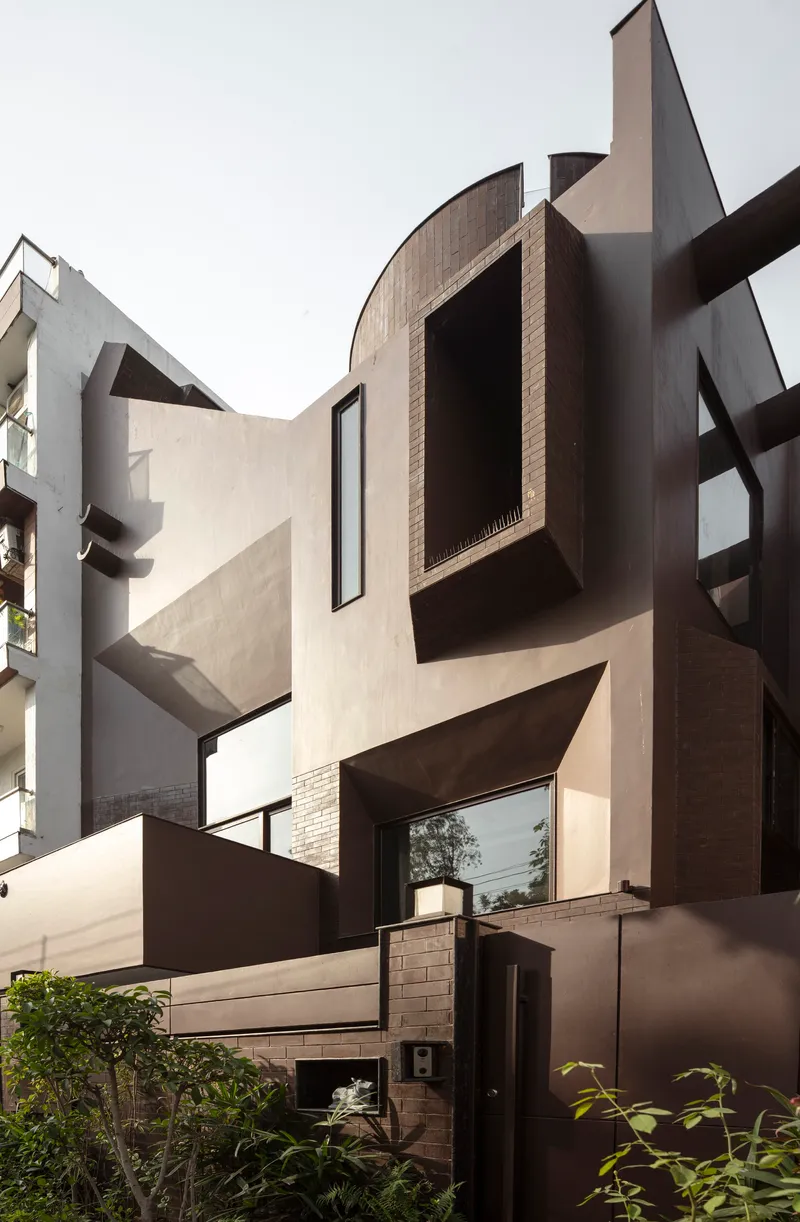 Courtyard view showing angular facade volumes with brown panels and protruding window boxes in daylight