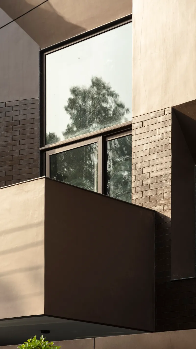 Stairwell view framed by brick walls and plaster surfaces with a tree visible through the window