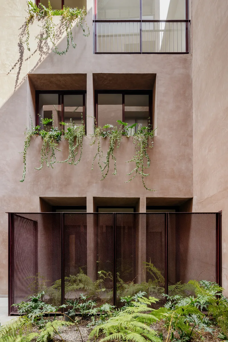 Interior facade showing planted window boxes with trailing greenery and perforated metal panels below