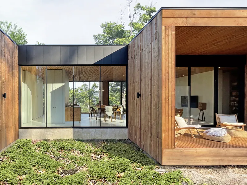 Courtyard view between timber-clad volumes with floor-to-ceiling glazing and ground cover plantings