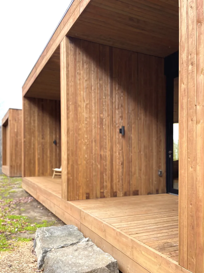 Covered timber deck with vertical board cladding and exposed post-and-beam structure