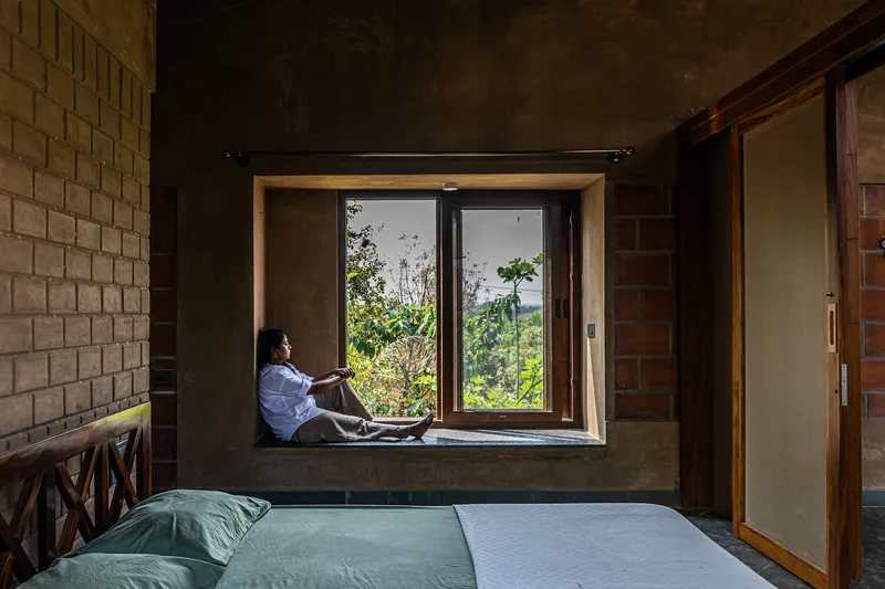 Deep window niche framing a seated figure looking out to forested hills beyond the casement