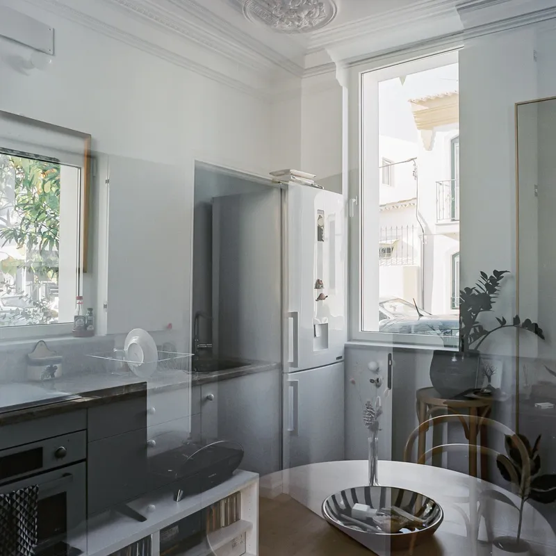 White kitchen interior with ornate ceiling medallion and tall windows overlooking neighboring buildings