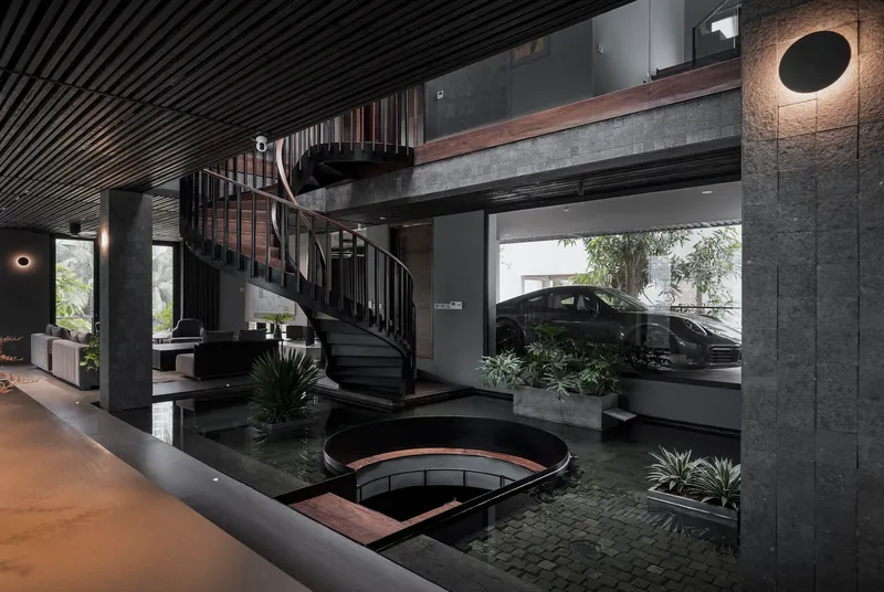 Double-height interior with black spiral staircase above a reflecting pool planted with agave and grasses