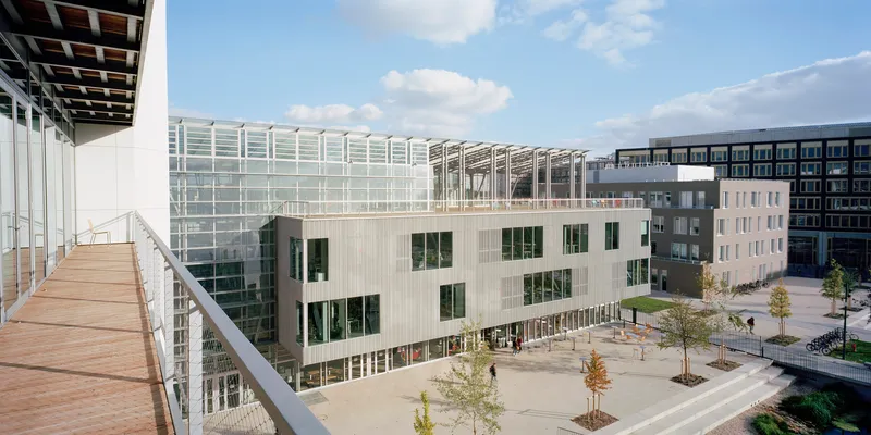 Elevated terrace view of the pale vertical cladding and glass rooftop structure across the courtyard