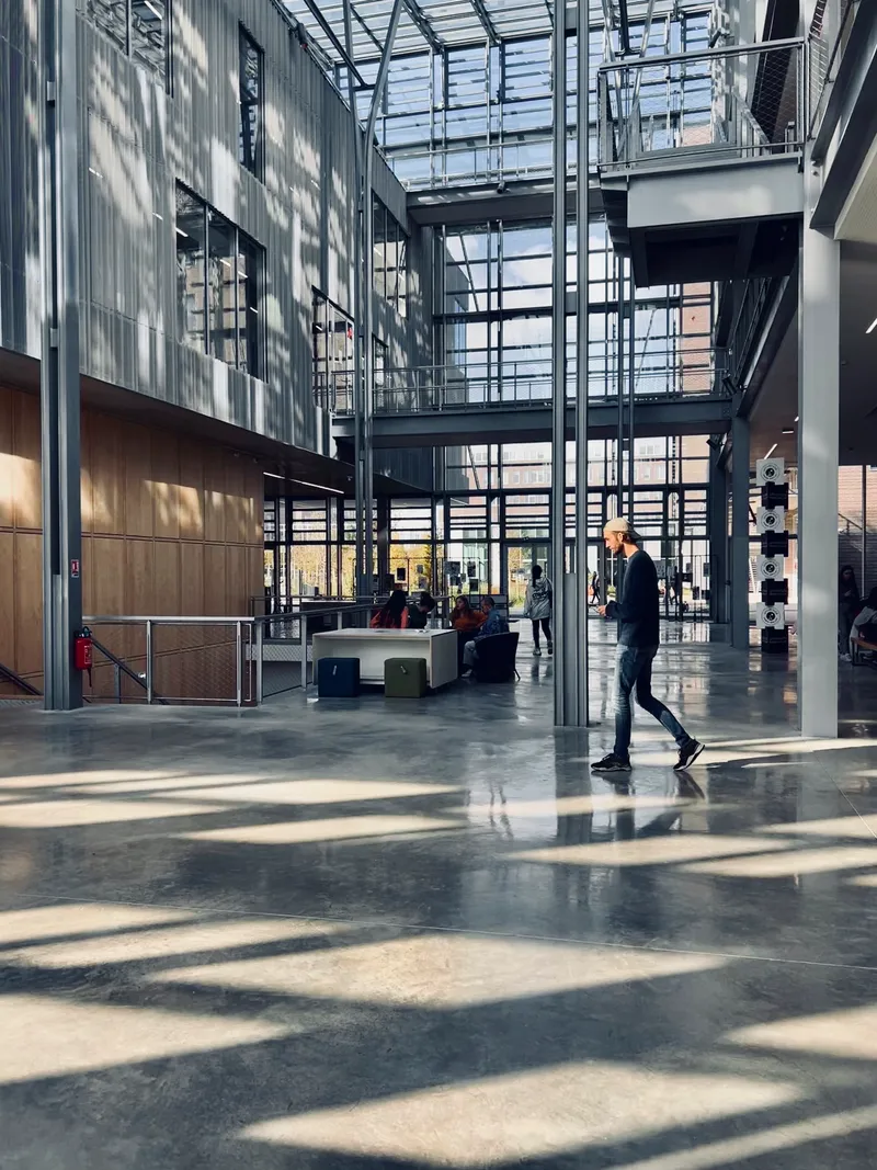 Atrium floor with patterned sunlight across polished concrete as a person walks past reception desk