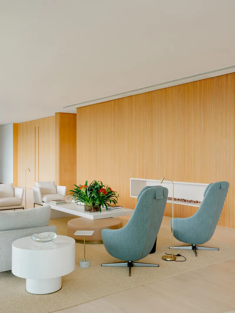Living room with vertical timber slat wall, turquoise swivel chairs, and potted tropical plants