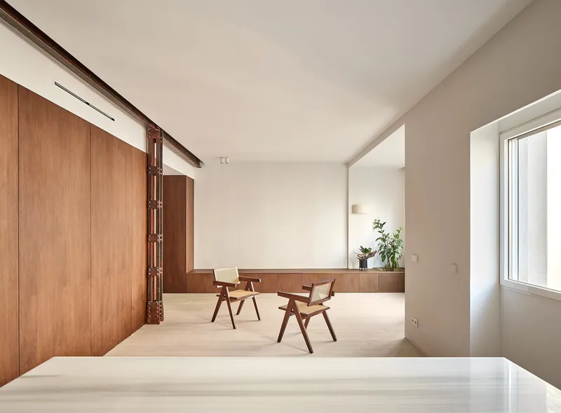 Open space with two wooden chairs beside a low timber bench and potted plants