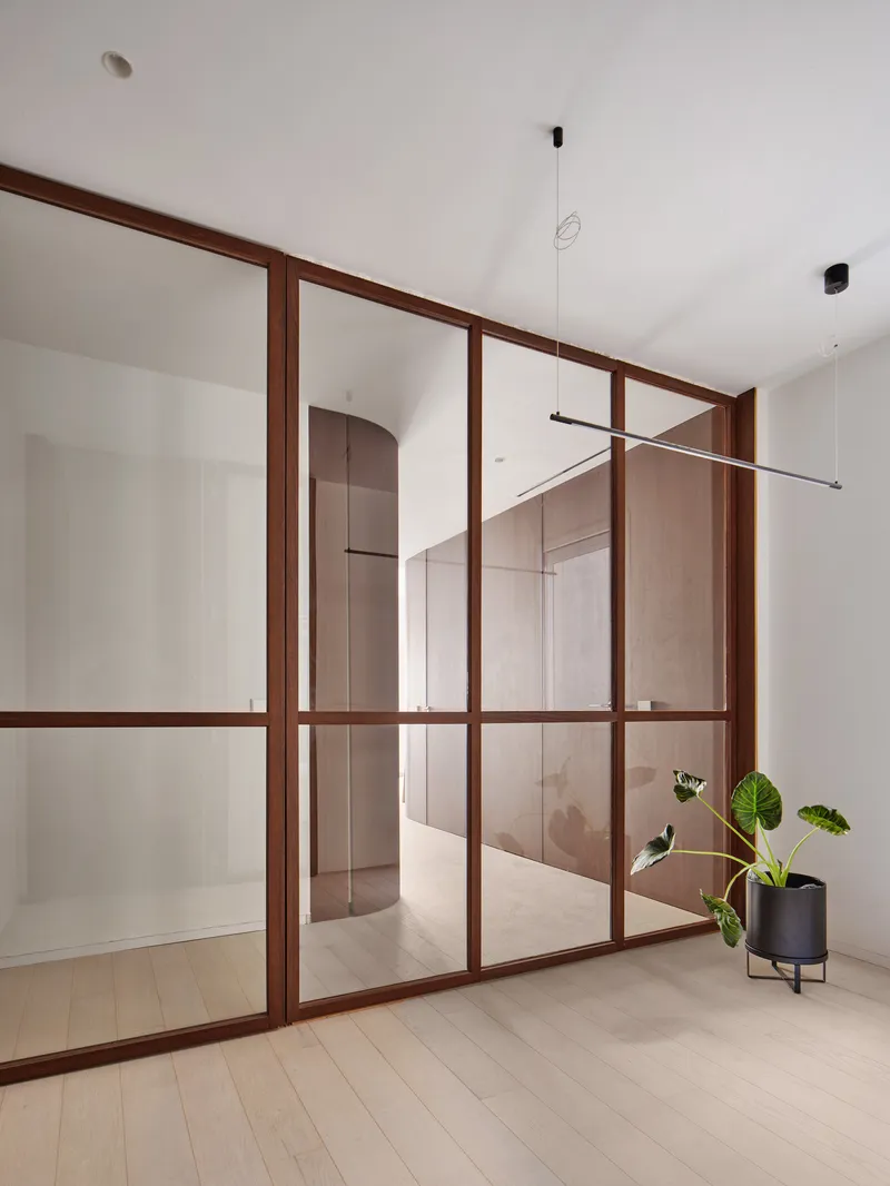 Timber-framed glass partition with pendant light and planters visible beyond the glazing