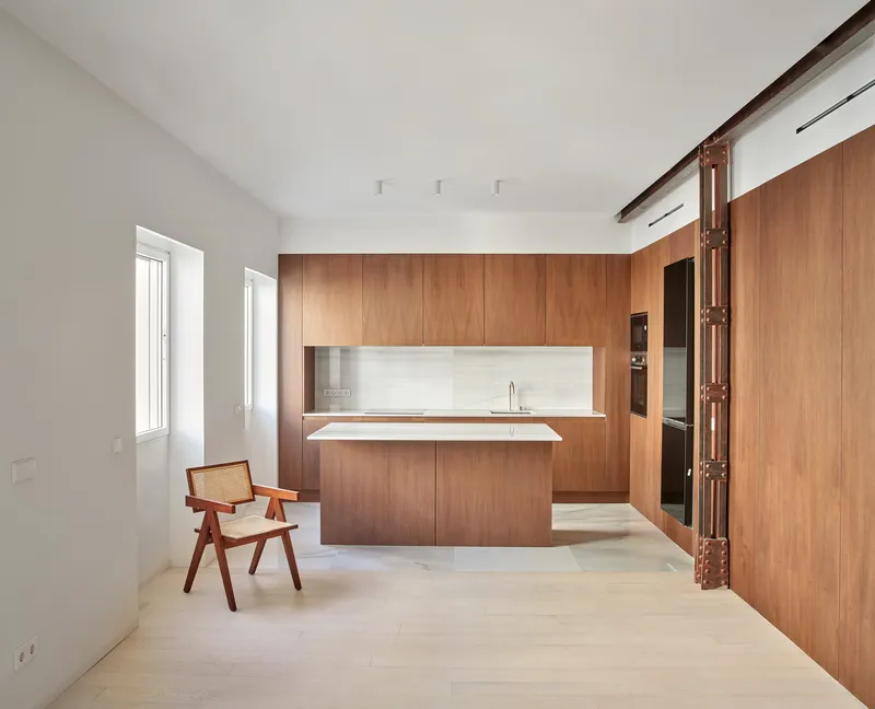 Kitchen with wood-clad island and backsplash beside two windows and a wooden chair