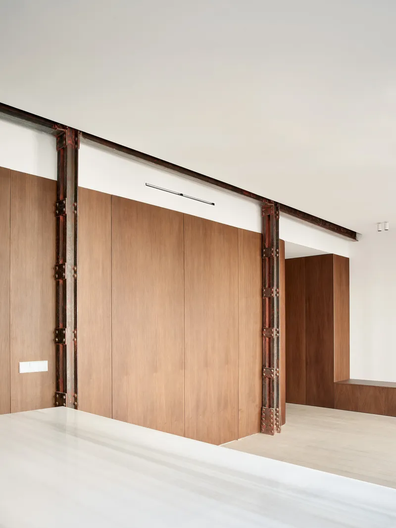 View across white stone countertop toward curved wood wall panels and exposed steel structure