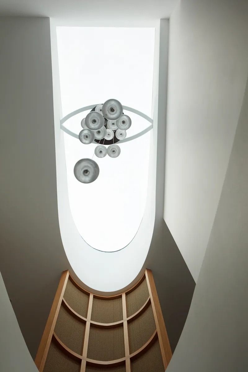 Upward view of glass sphere chandelier suspended in the curved void above oak cane balustrade