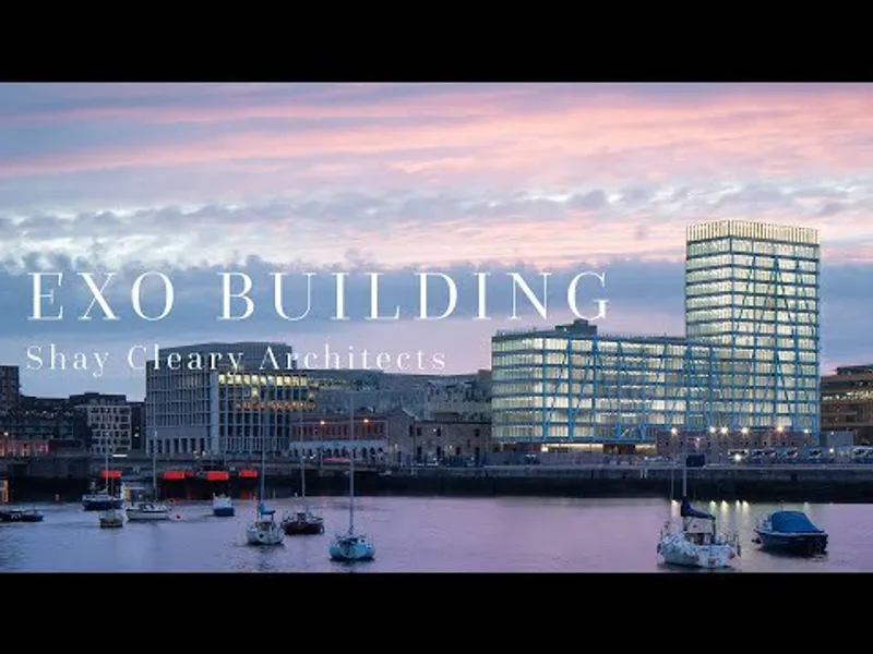 Glass and steel tower rising above a waterfront with moored sailboats at dusk