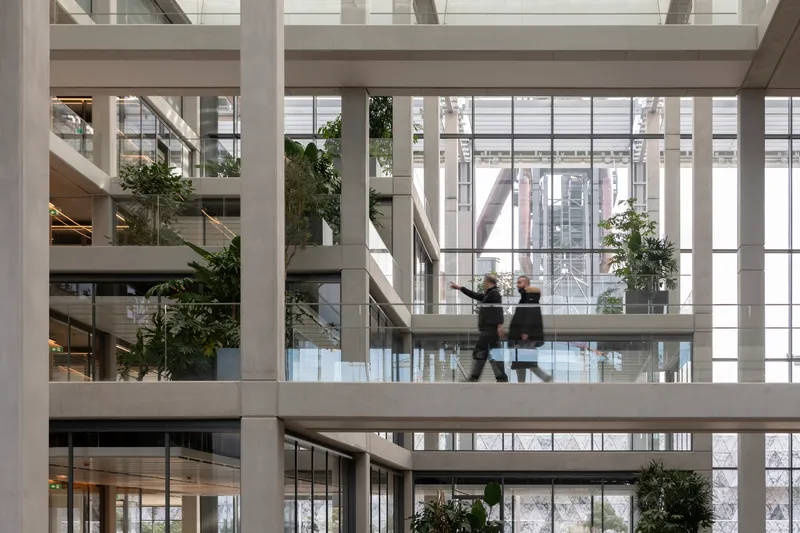 Atrium walkway with two figures in motion and greenery on tiered levels
