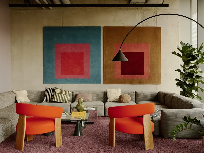 Seating area with two square canvas artworks above a sectional sofa and arched floor lamp