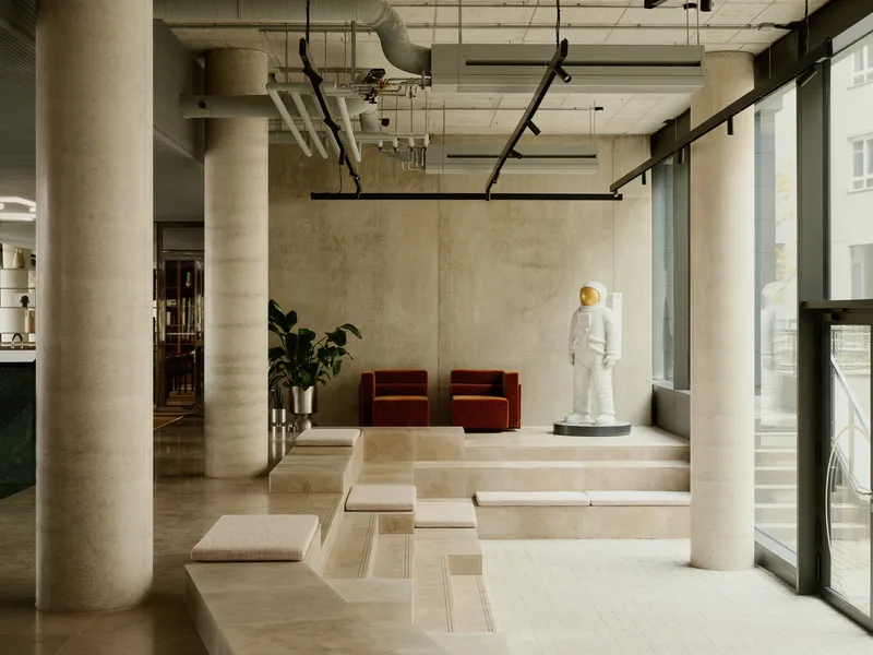 Raised platform with stone steps, cylindrical columns, and red velvet chairs near full-height windows