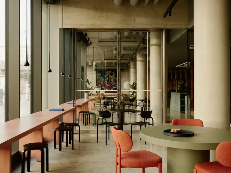 Dining area with pendant lights, mixed seating, and views through glass partitions to adjacent spaces