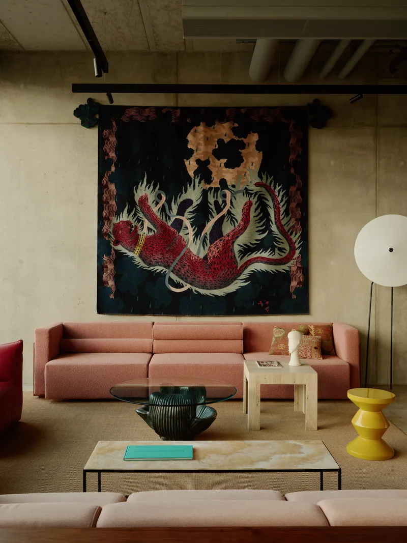 Close-up of seating beneath the dragon tapestry with exposed concrete ceiling and track lighting