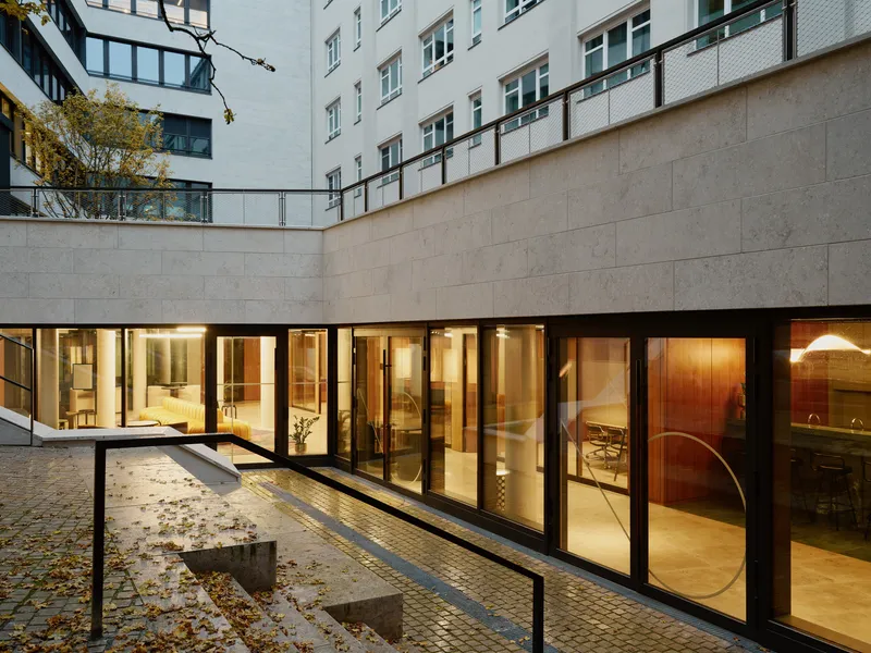 Courtyard view with limestone walls, glazed ground floor openings and scattered autumn leaves