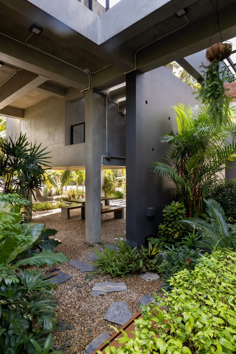 Courtyard pathway with exposed concrete beams and stepping stones through gravel and planted beds
