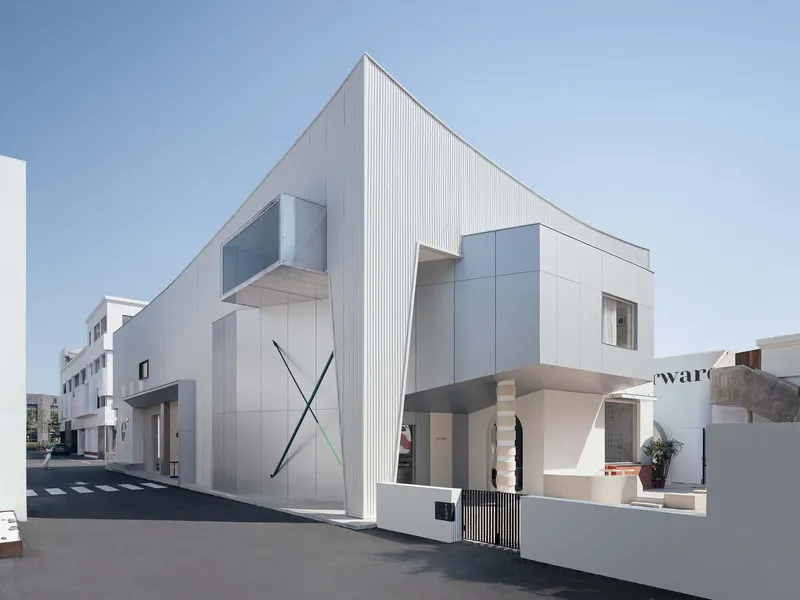 Street view of the white facade with vertical ribbed cladding and cantilevered window box