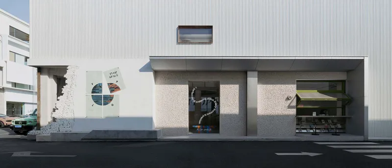 Ground level facade showing exposed brick wall fragments alongside grey stucco panels and storefront openings
