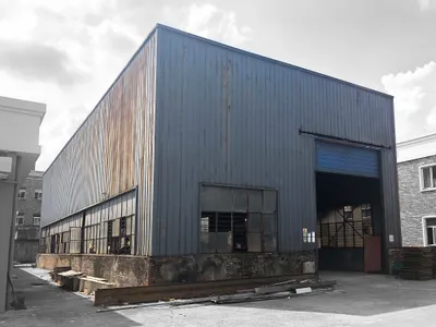 This architectural image showcases an industrial warehouse building with a metal-clad exterior and a