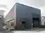 This architectural image showcases an industrial warehouse building with a metal-clad exterior and a