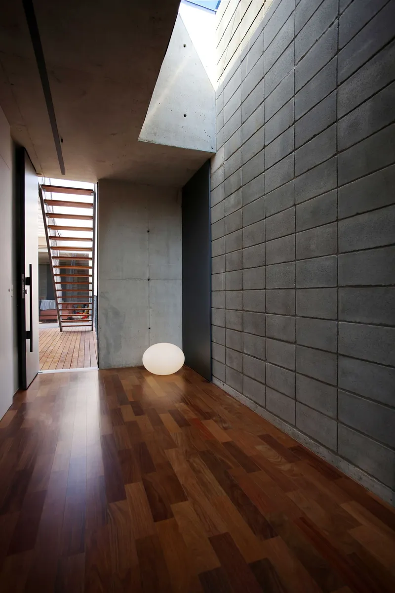 Interior hallway with grey concrete block wall and timber floor lit by overhead skylight