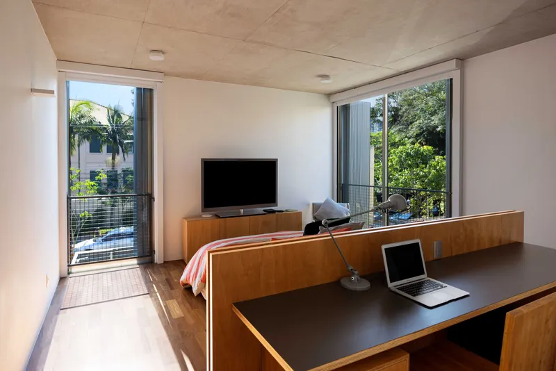 Living space with timber built-in furniture and glass doors opening to balcony with greenery