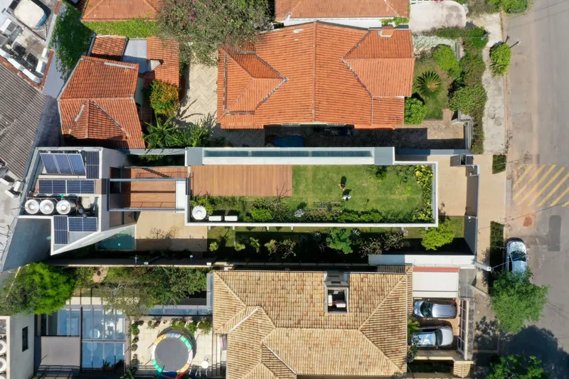 Aerial view showing lap pool and lawn courtyard between residential volumes with terra cotta roofs