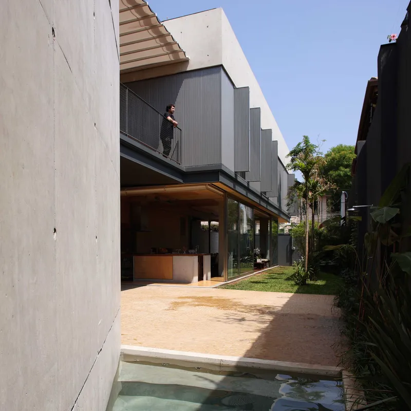 Courtyard view showing concrete paver terrace with shallow water basin and metal-clad upper volume