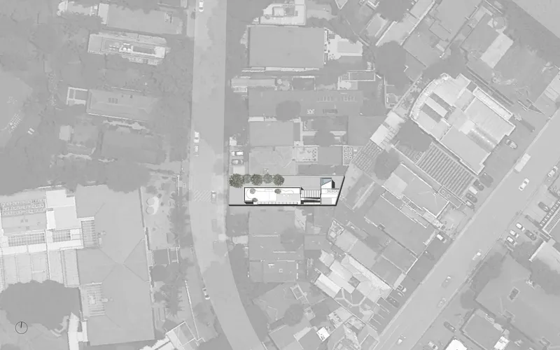 Aerial site plan drawing showing rectangular building footprint with courtyard and tree canopies within dense urban fabric