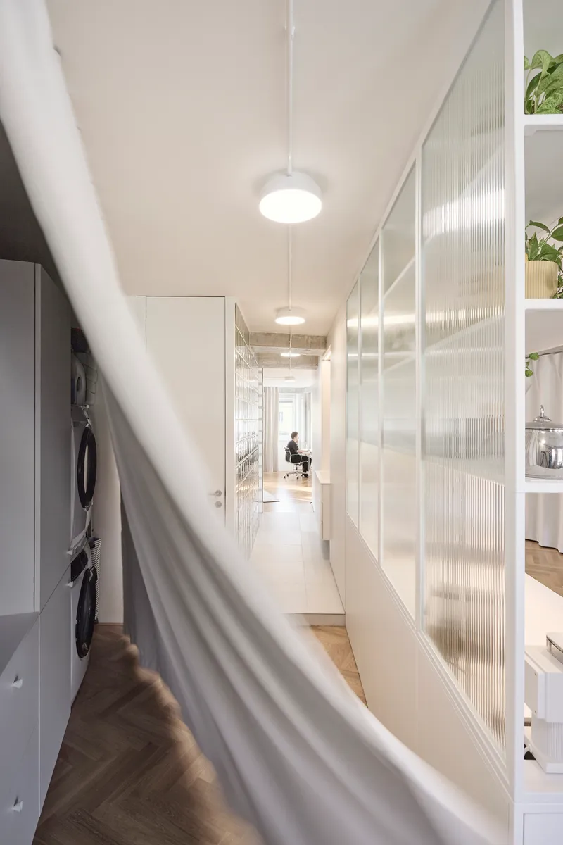 Long hallway view with translucent ribbed glass panels and white curtain in foreground