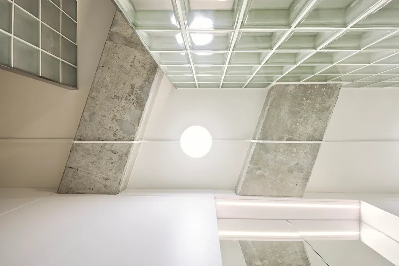 Upward view of coffered ceiling with angled concrete beams meeting at a central globe light