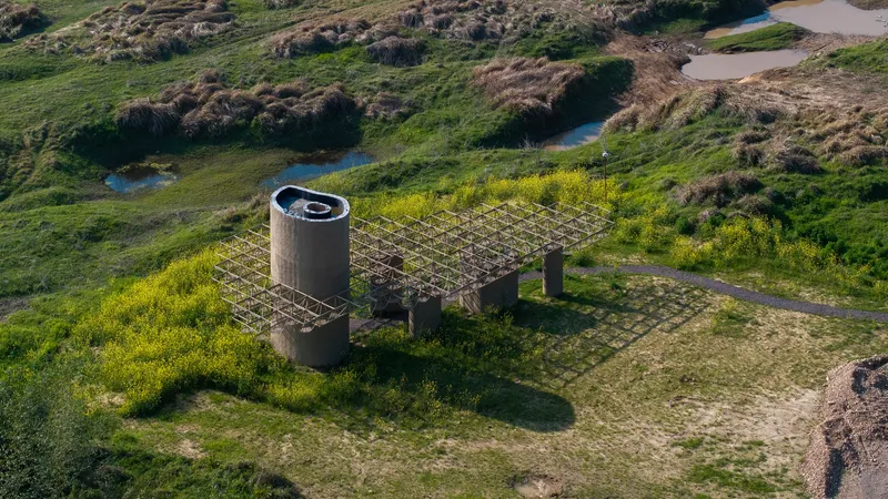 Aerial view of the concrete tower and timber-framed canopy surrounded by flowing green meadows and marshland