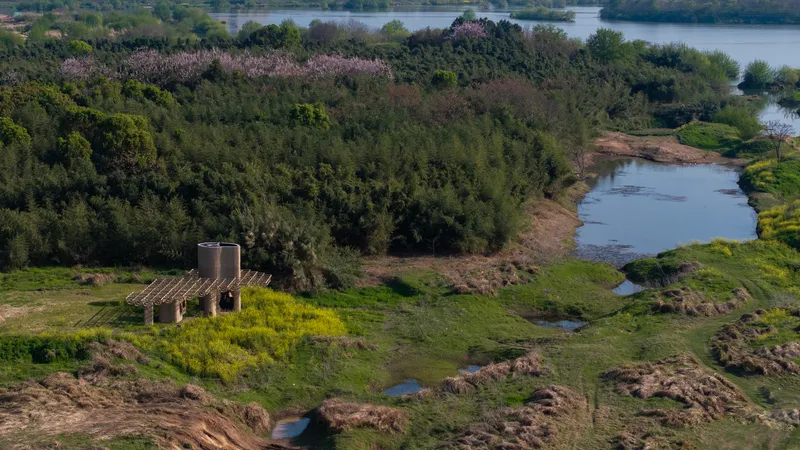 Drone perspective of the observation structure nestled between water channels and flowering trees in the riverside landscape