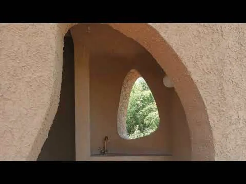 Vaulted niche with an organic shaped window opening framing green foliage beyond
